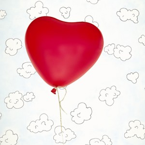 Small child's hand holding heart-shaped balloon